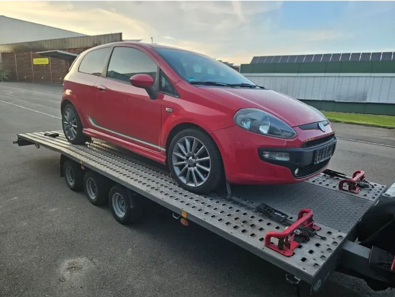 Roter Kleinwagen auf einem Fahrzeugtransportanhänger